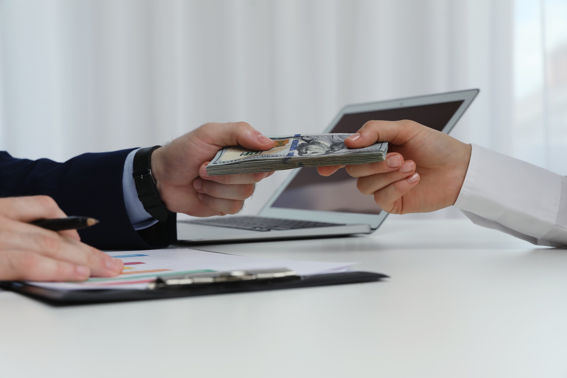 Cashier giving money to businesswoman at desk in bank, closeup